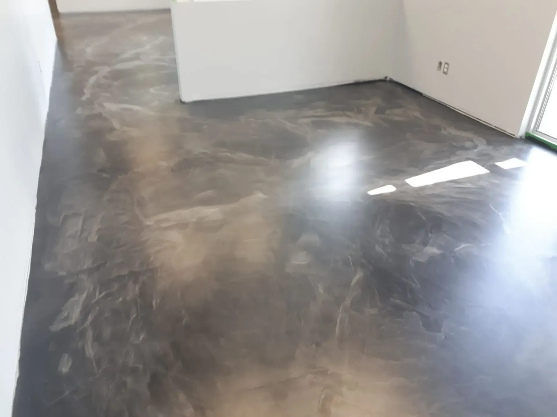 A shiny concrete floor in a room with white walls.
