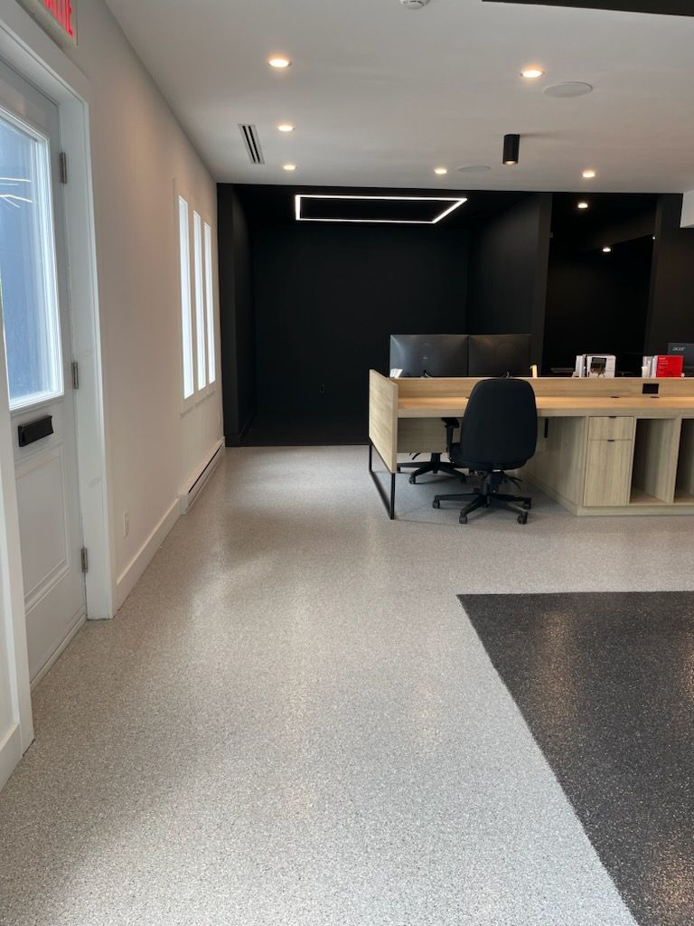 Modern office interior with speckled flooring, desk, and black accent wall.