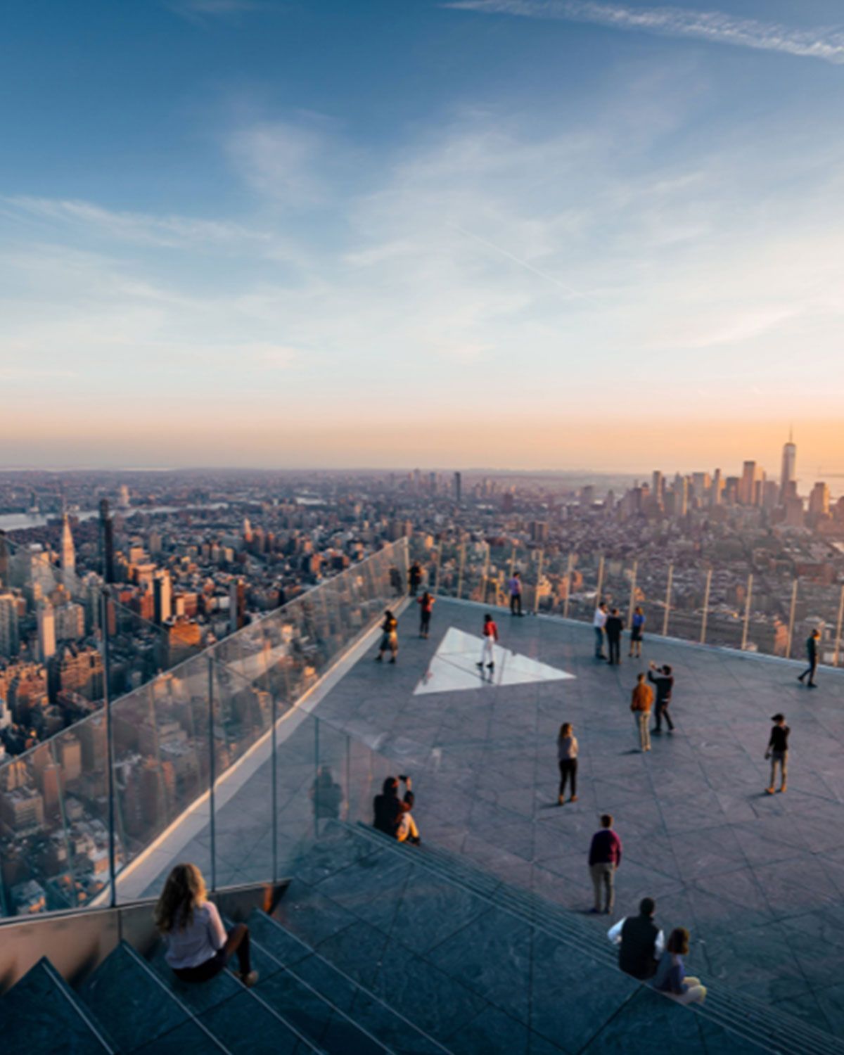 A group of people are standing on top of a staircase overlooking a city.