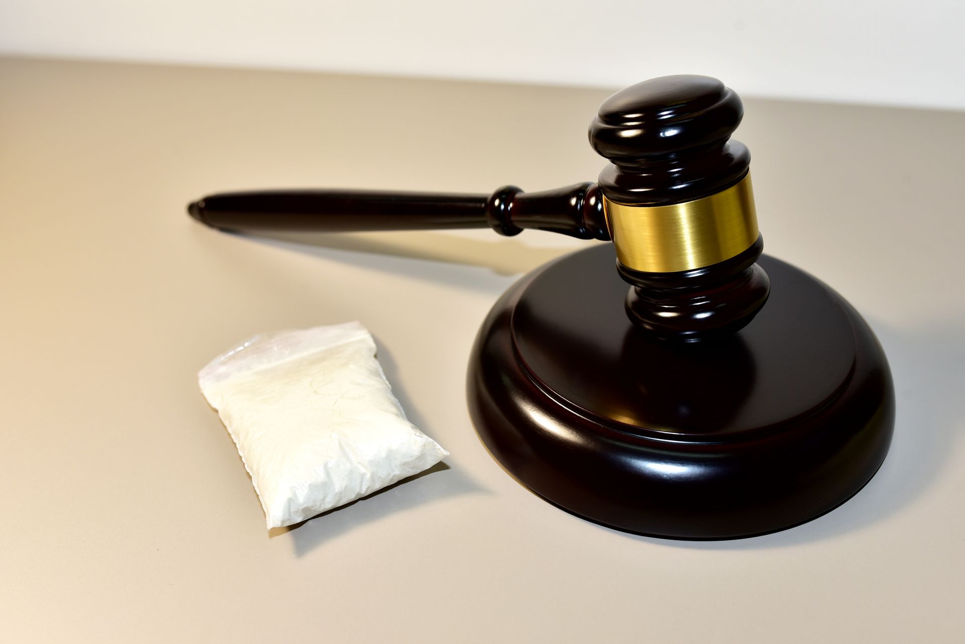 A gavel on a stand next to a small bag of white powder, drug possession charges in Florida.