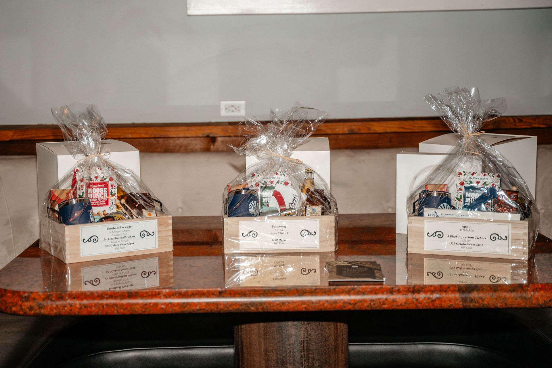 Three gift baskets on a shelf, each wrapped in cellophane.