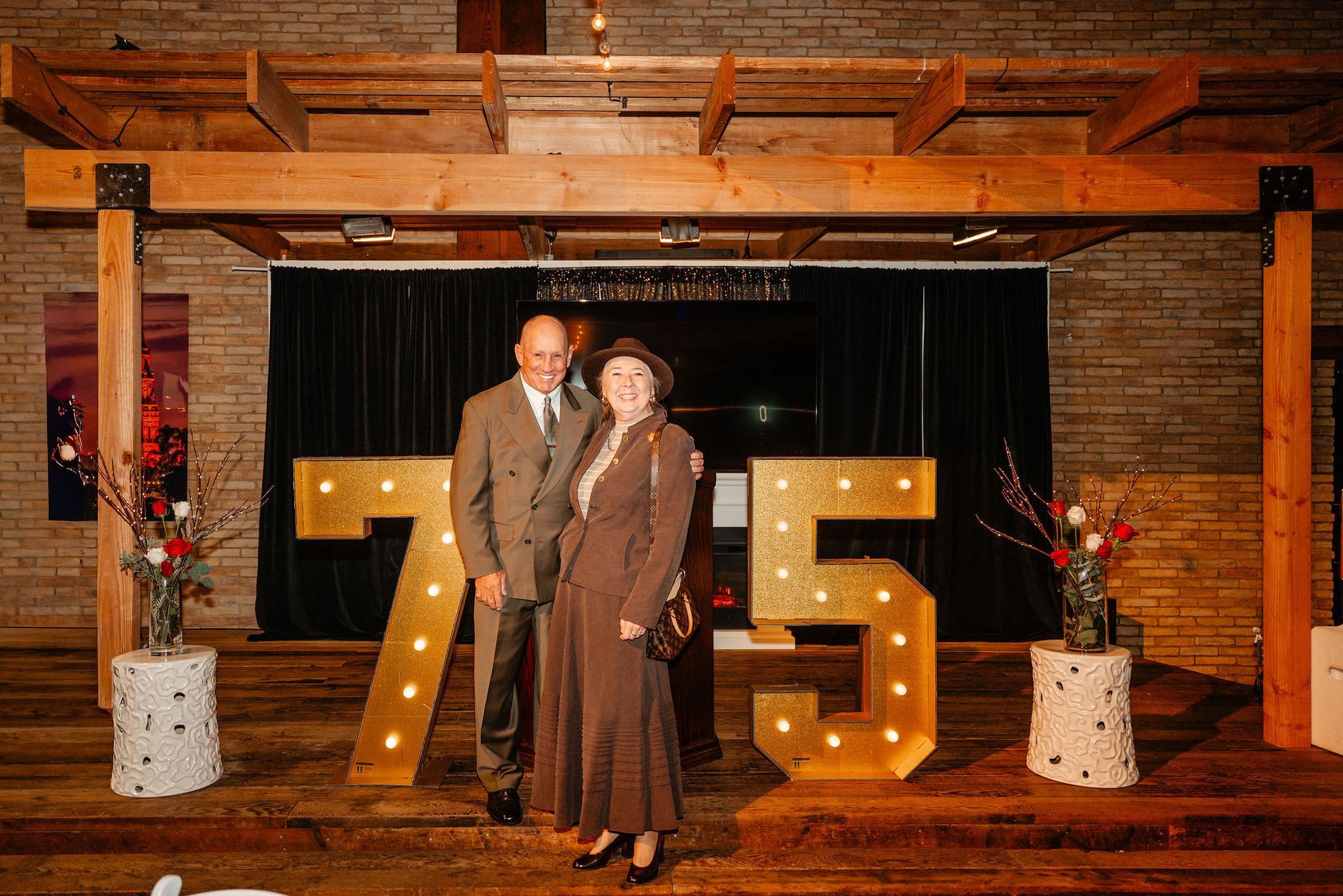 Couple poses beside lighted 