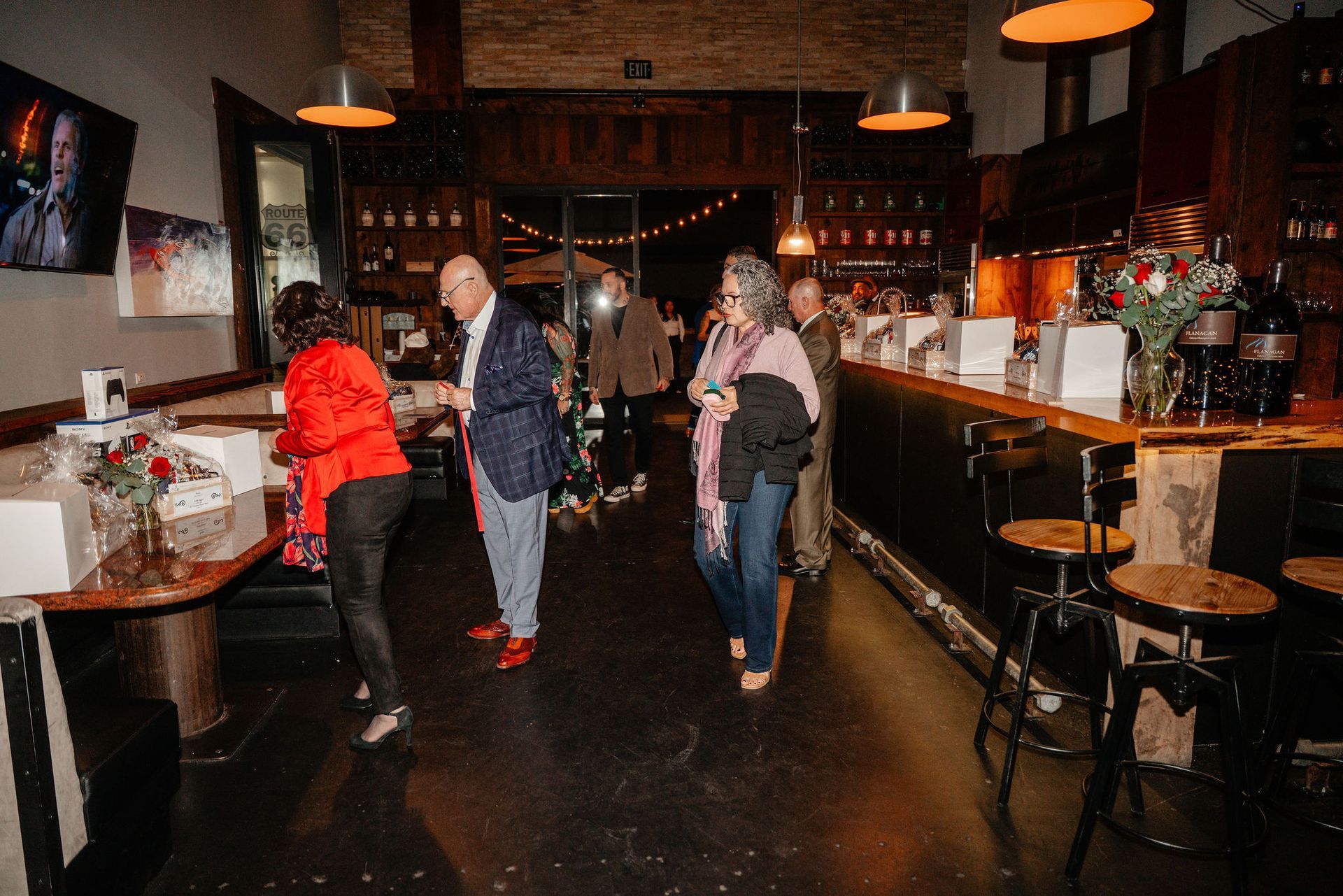 People mingling at a bar, with dim lighting and a rustic interior, including a person wearing red shoes.