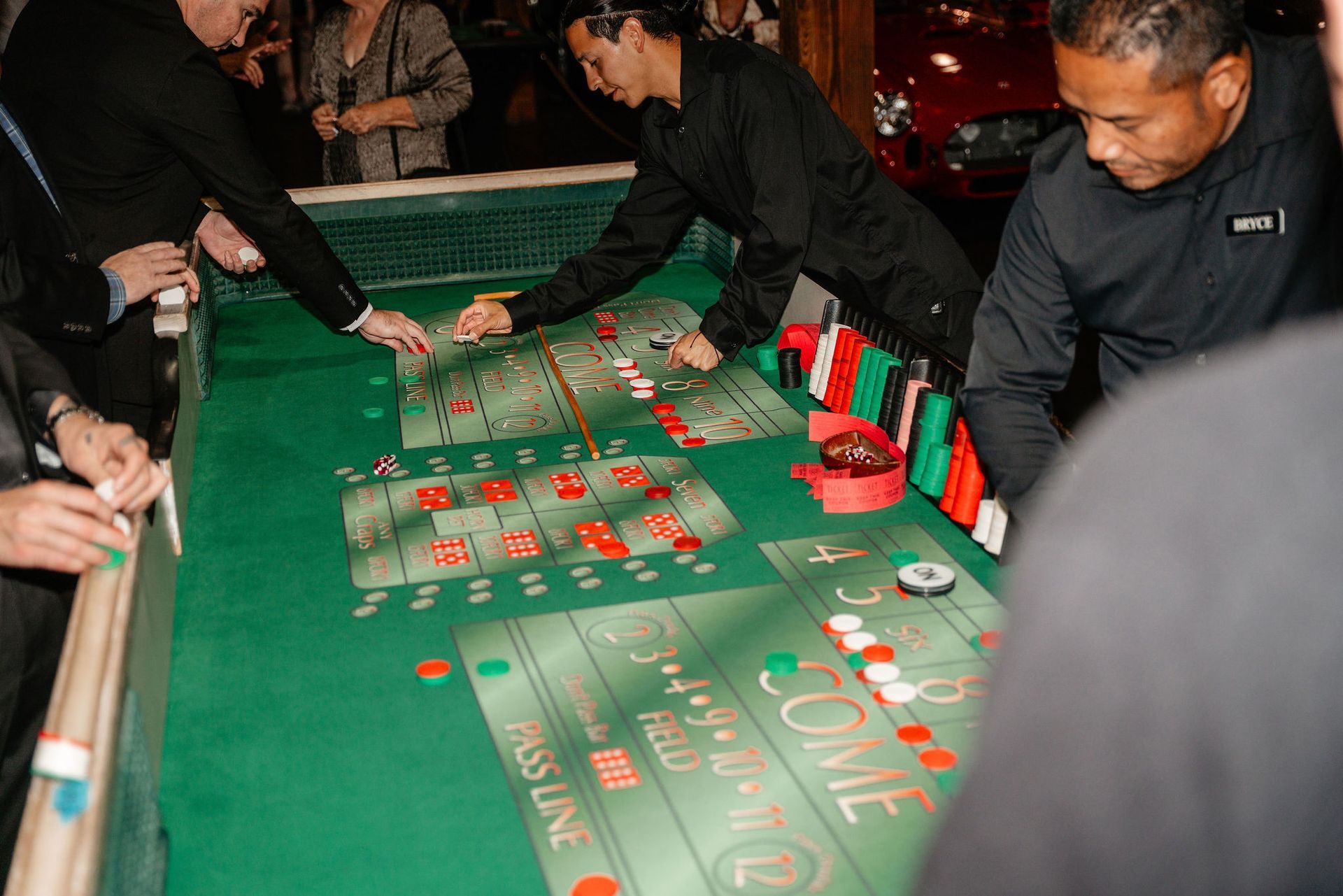 People playing craps at a casino table, betting with chips. Green felt, red and white chips visible.