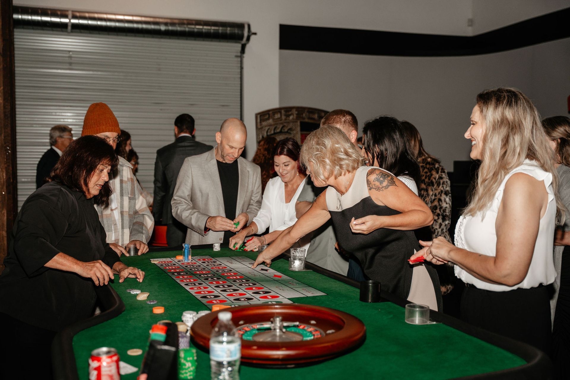 People playing roulette at a casino party, set in a room with a garage door.