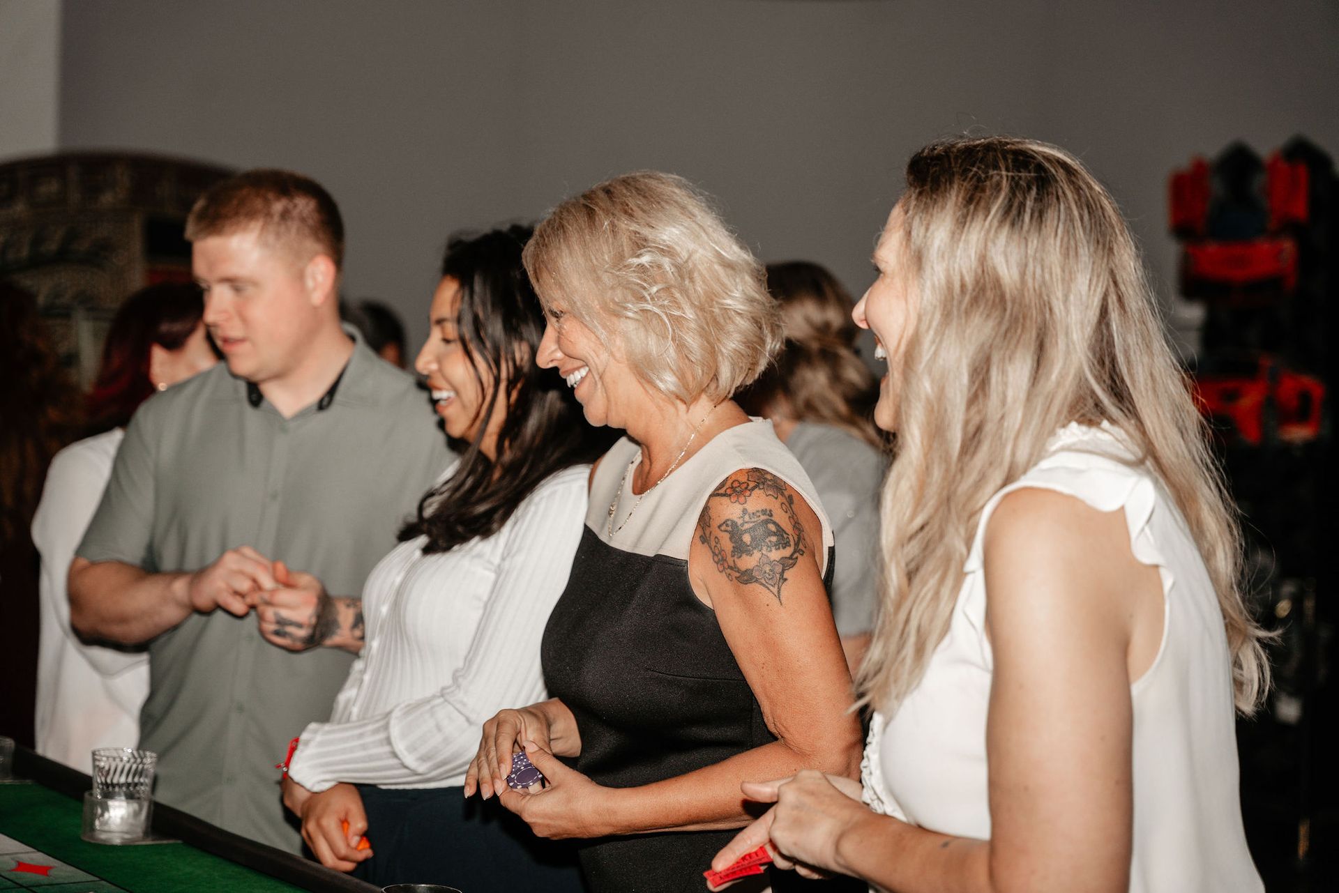 People smiling and laughing, standing around a table at an event.