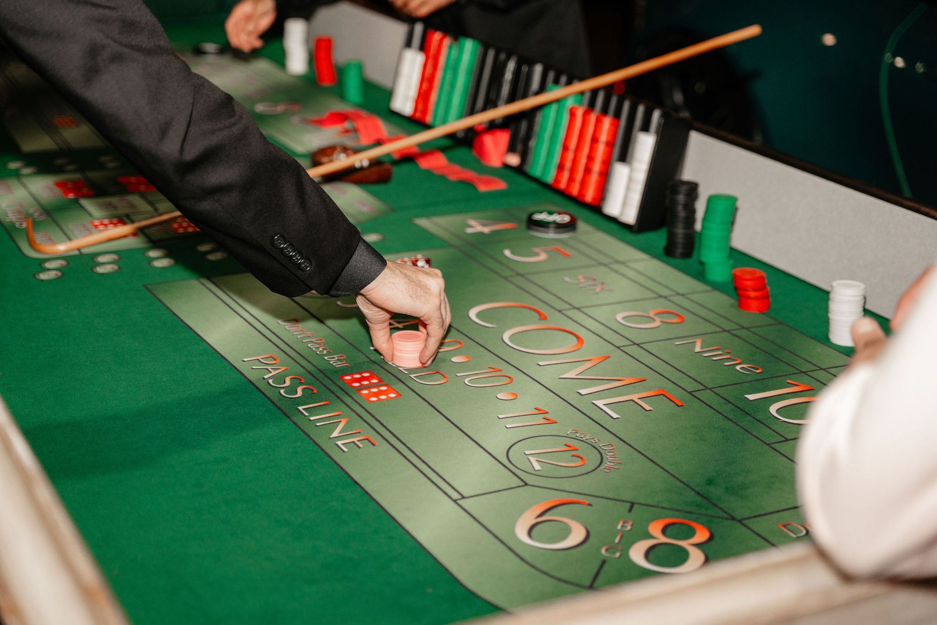 Person placing chip on a craps table; green felt, chips, and dice visible.