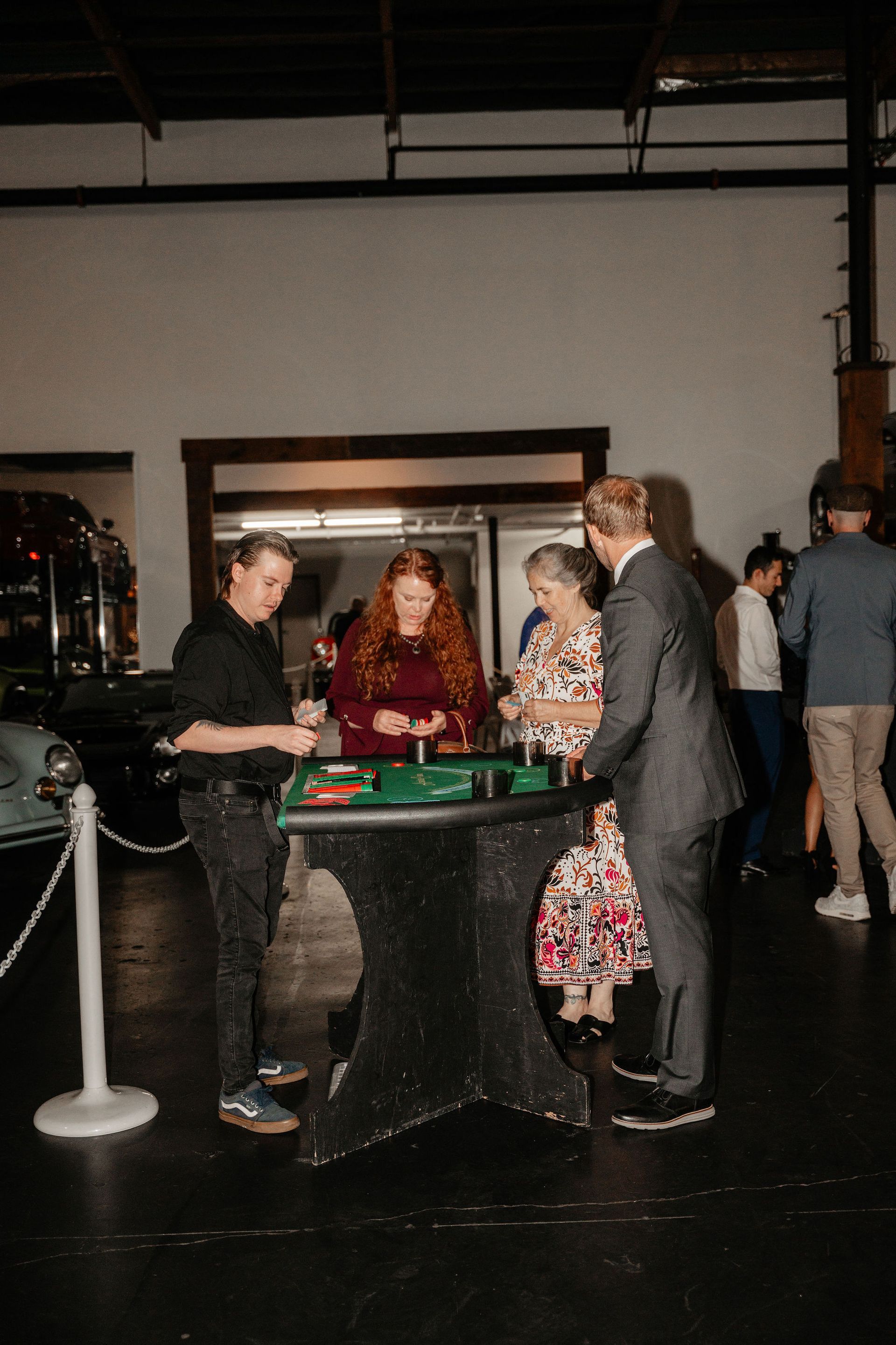 People playing roulette at a party. The croupier and players surround the table in a dark room.