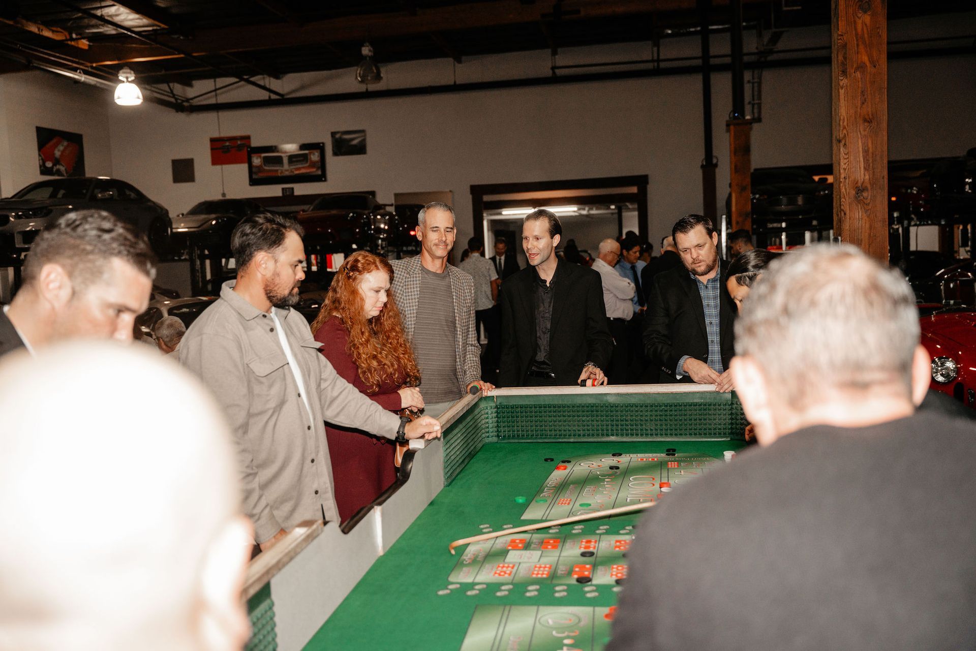 People gathered around a green table playing a game in a garage-like setting.