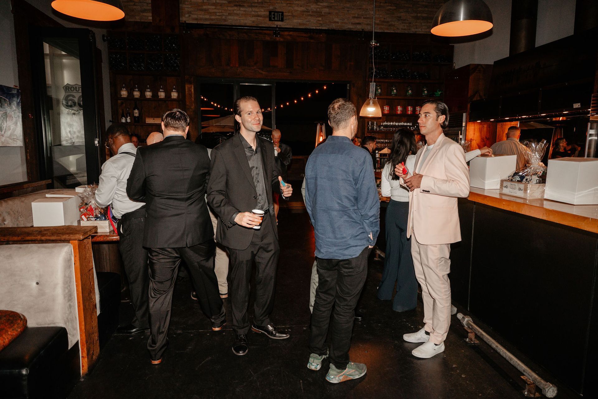 People socializing at a dimly lit bar, some holding drinks.