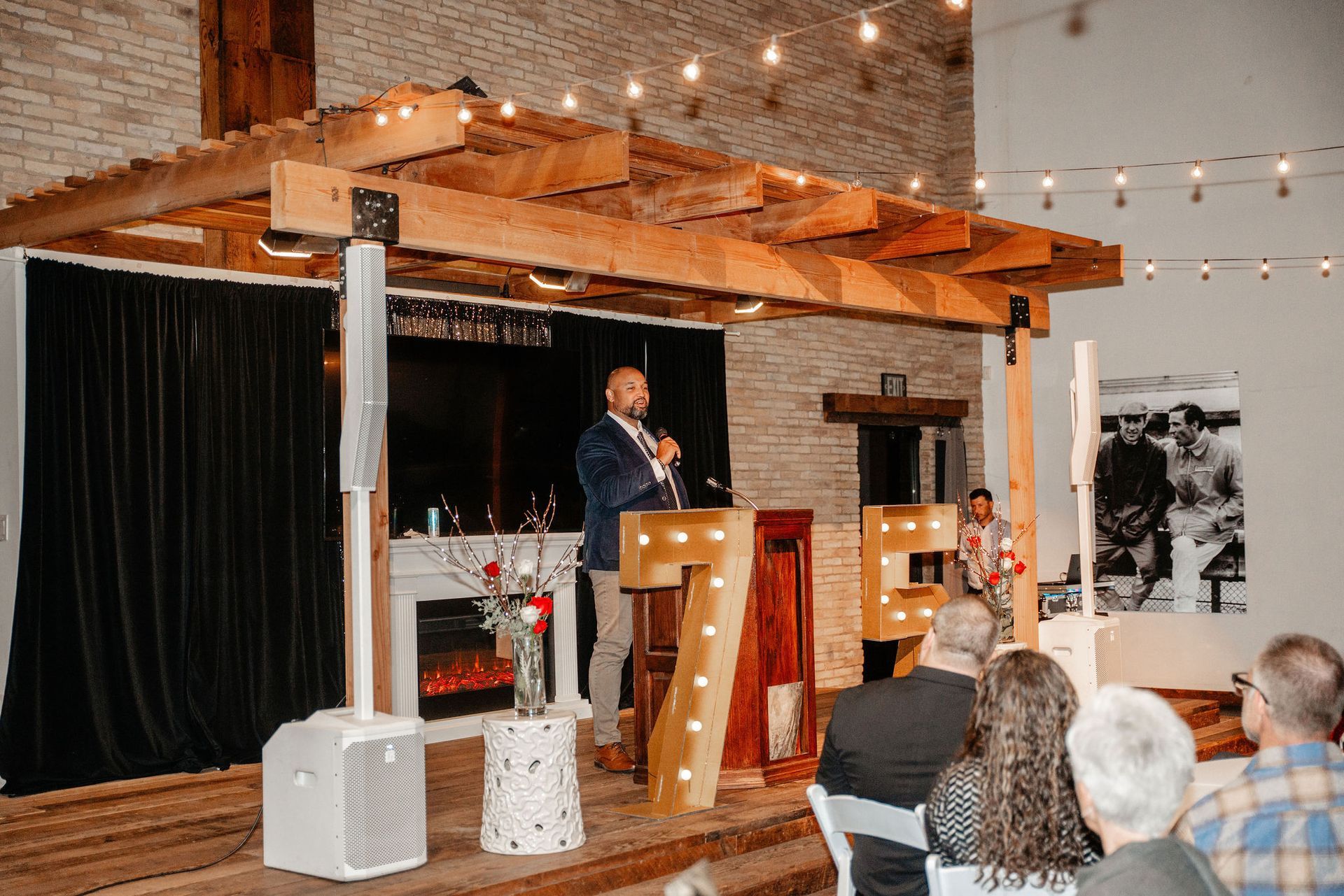 Man speaking at podium, illuminated letters 