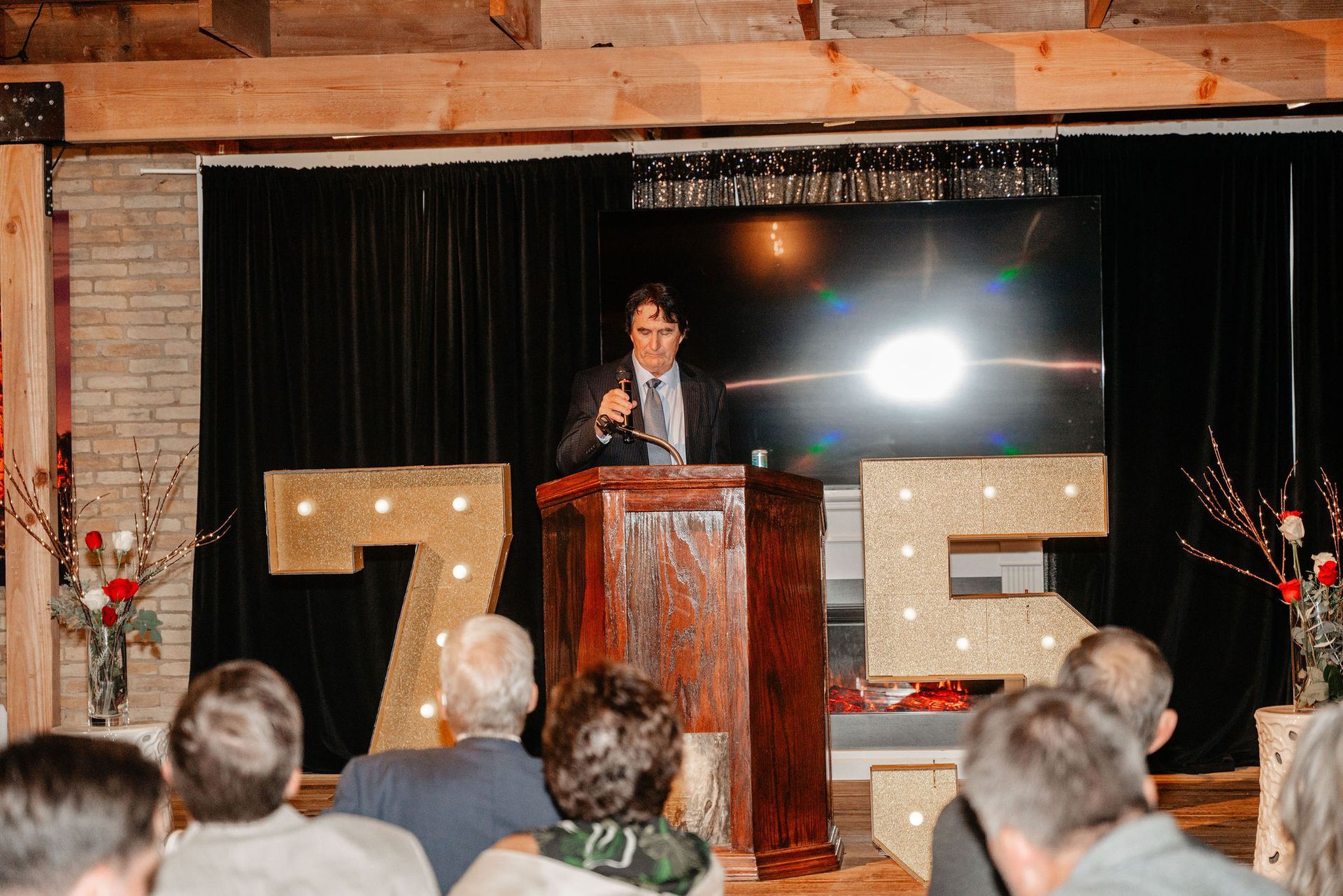 A man speaking at a podium. Event in a room with a large screen, 