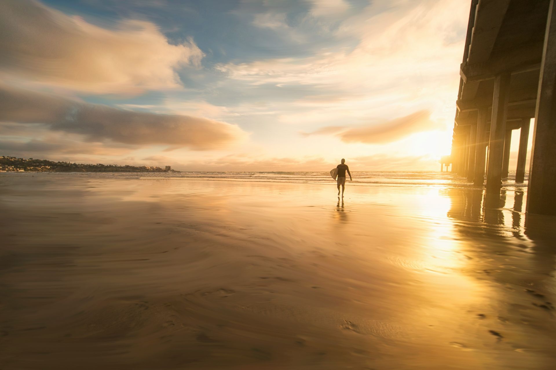 A person is walking on a beach at sunset.