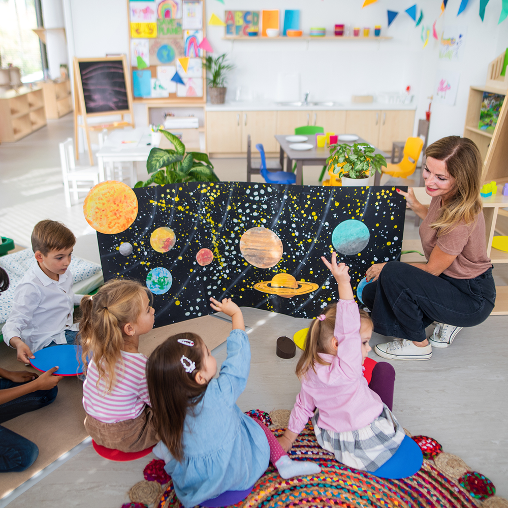 Teacher Showing A Poster With Planets — Columbia, IL — Columbia Kinder College