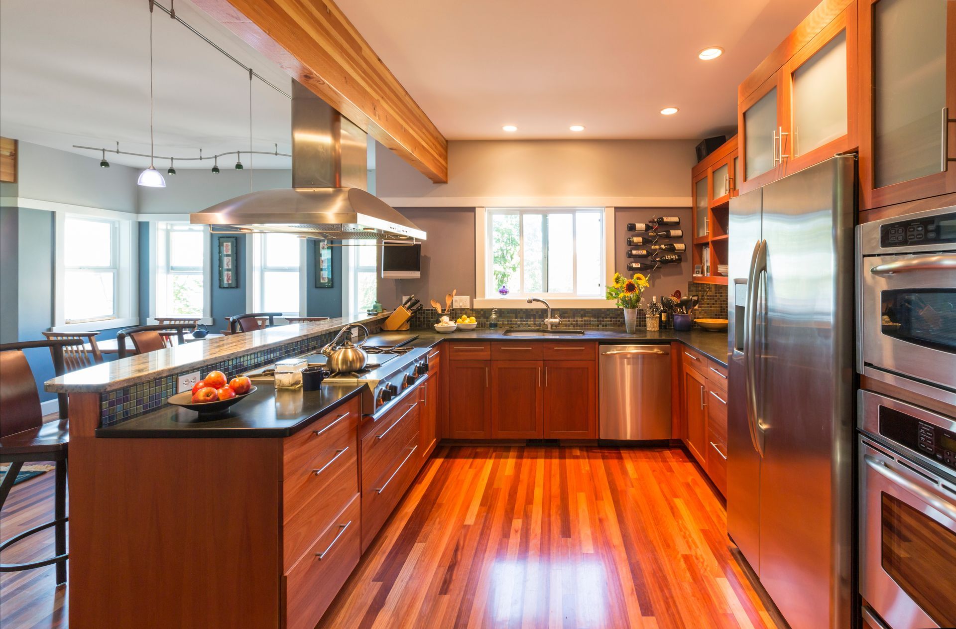 Upscale kitchen with hardwood floors, wood cabinets, accent lighting & stainless steel.