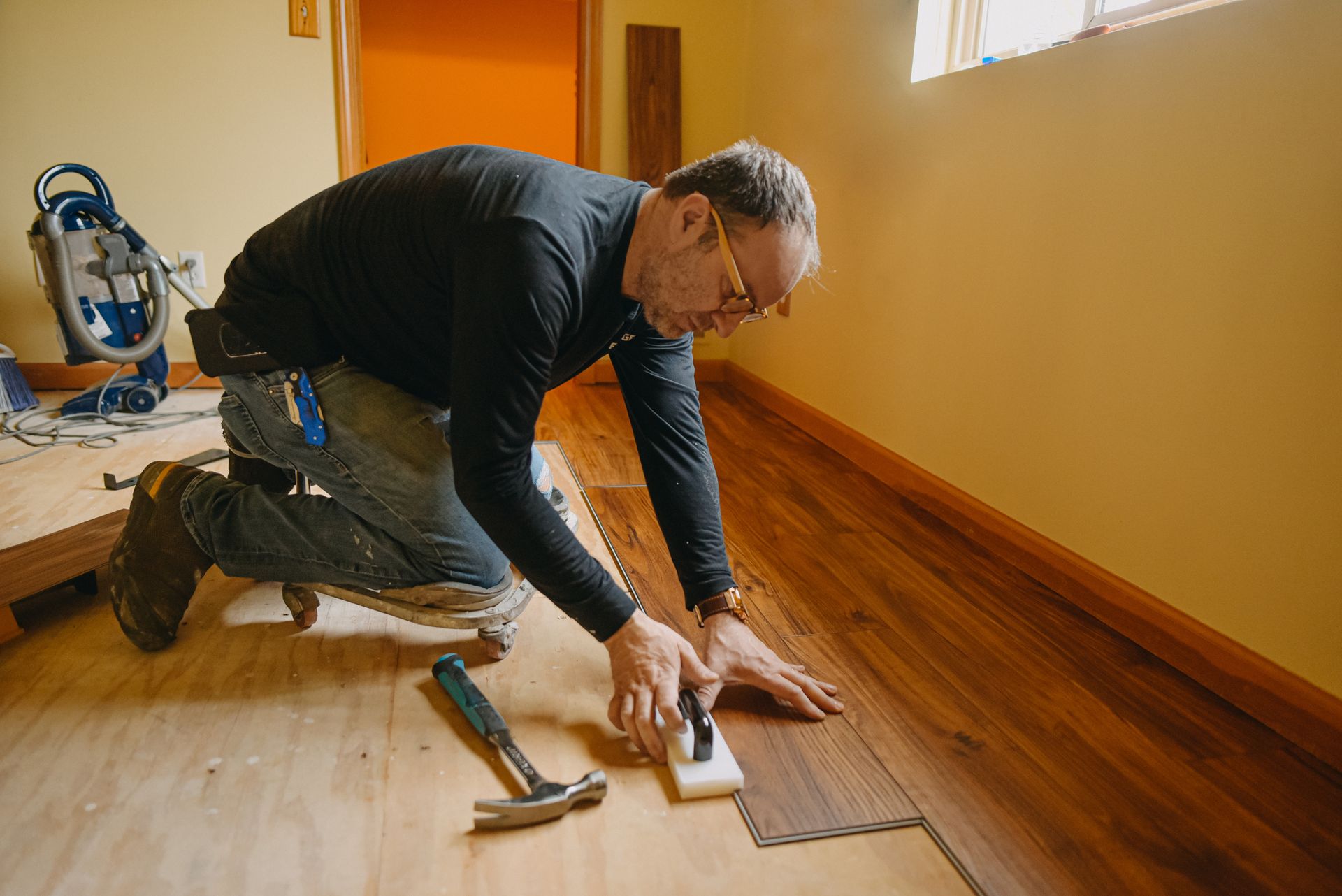 A man working on hardwood flooring at home, showcasing skills as a hardwood flooring contractor.