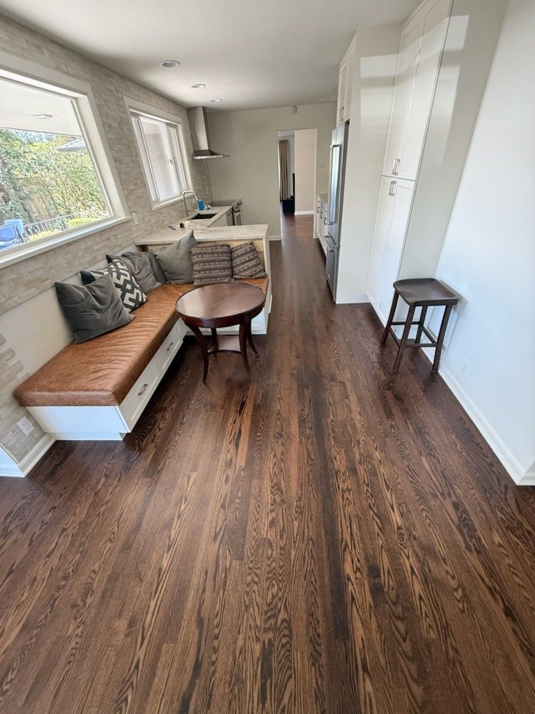 Aerial view of a living room and entrance area with hardwood floors, a couch, and a patterned rug.