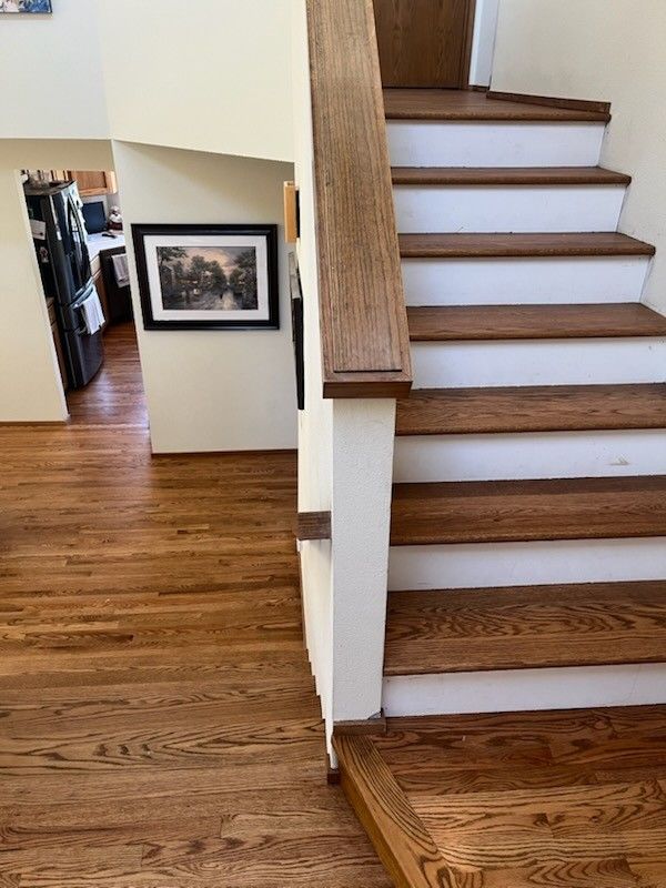 View of a wooden staircase with white risers and a small hallway featuring a framed black and white picture.
