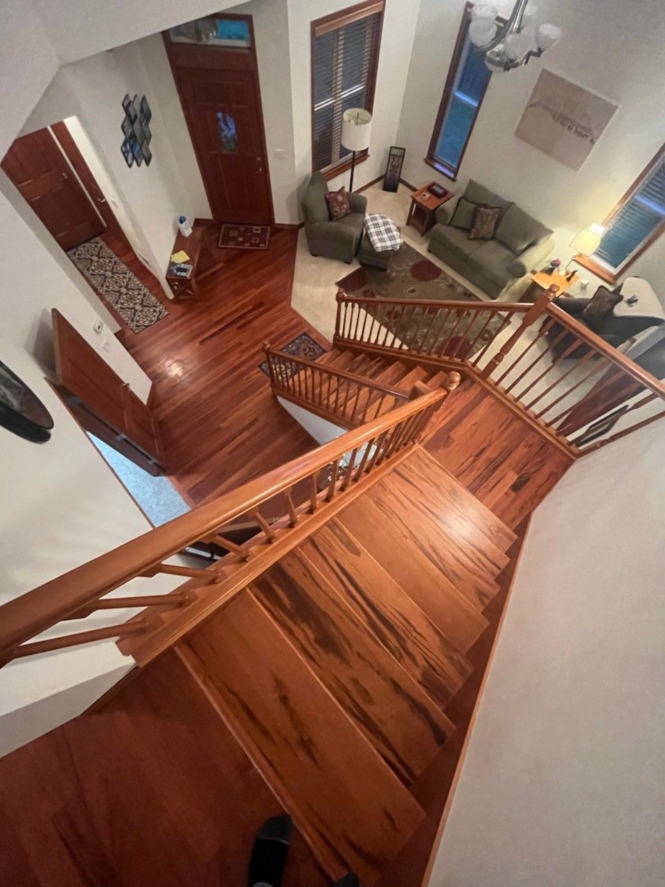 Aerial view of a living room and entrance area with hardwood floors, a couch, and a patterned rug.
