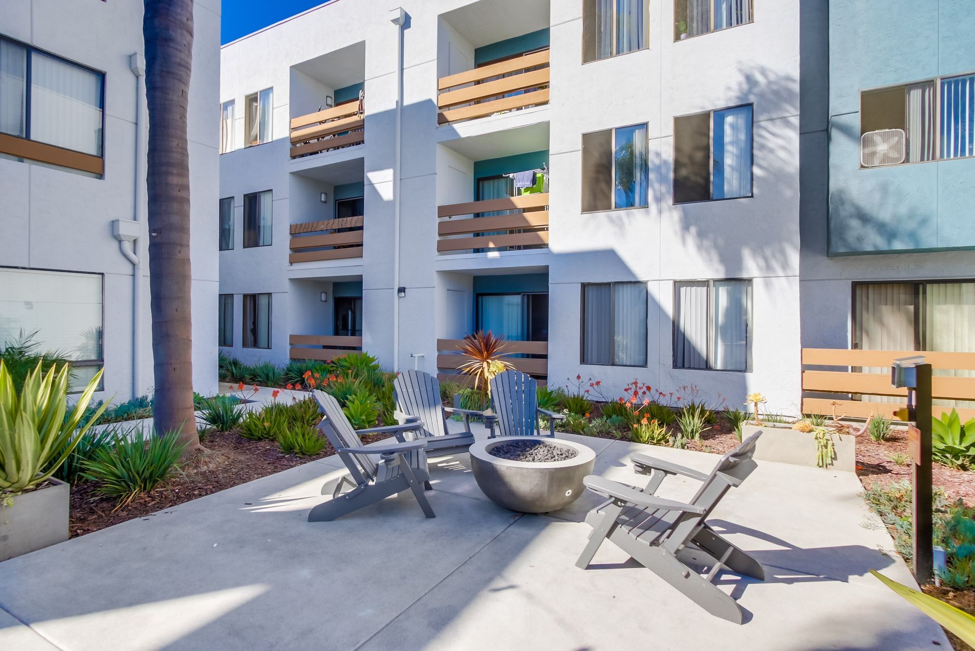 Courtyard with chairs around a fire pit, surrounded by apartment buildings and landscaping.