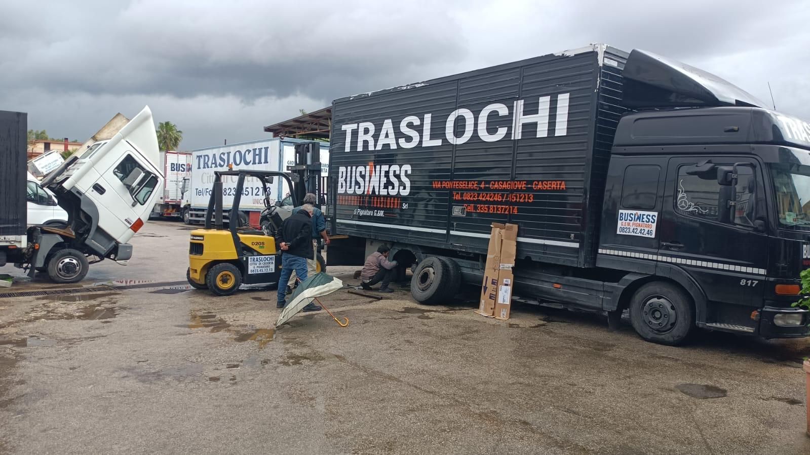 Un camion nero con la scritta traslochi sulla fiancata è parcheggiato in un parcheggio.