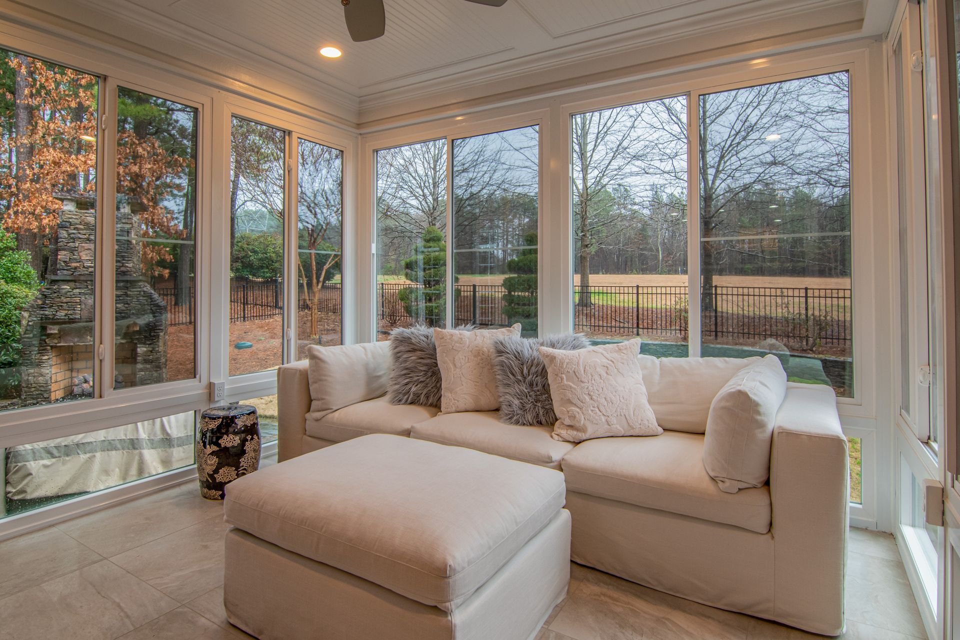A living room with a couch and ottoman and lots of windows