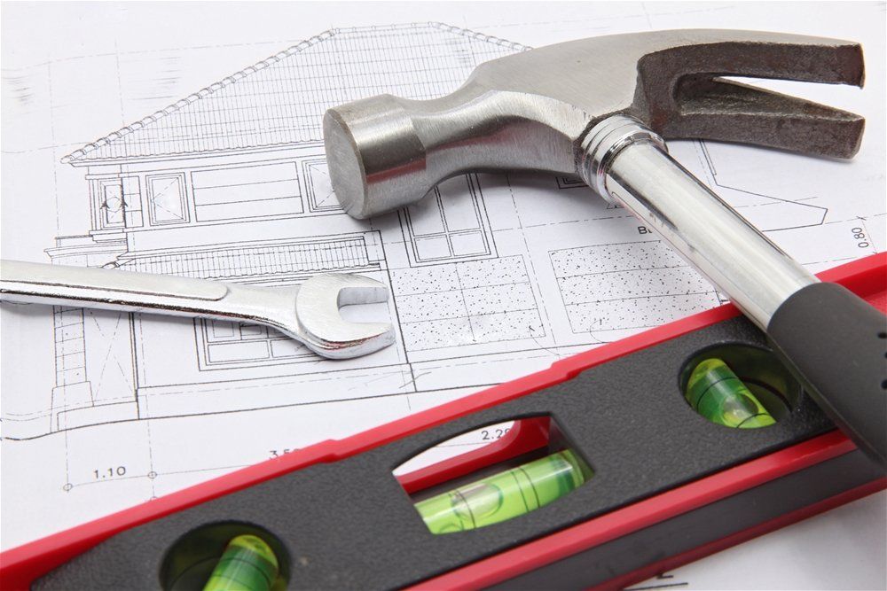 Hammer, wrench, and level on architectural blueprint, tools for construction.