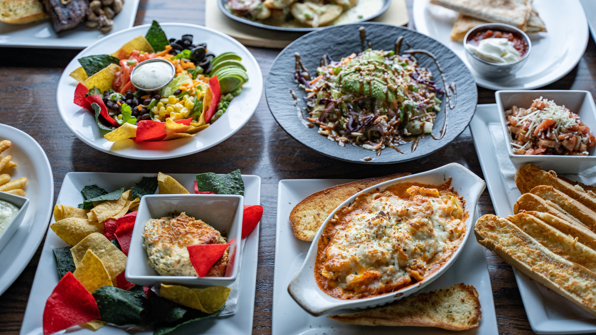 Overhead shot of multiple dishes on a table: salad, pasta, appetizers, and bread.
