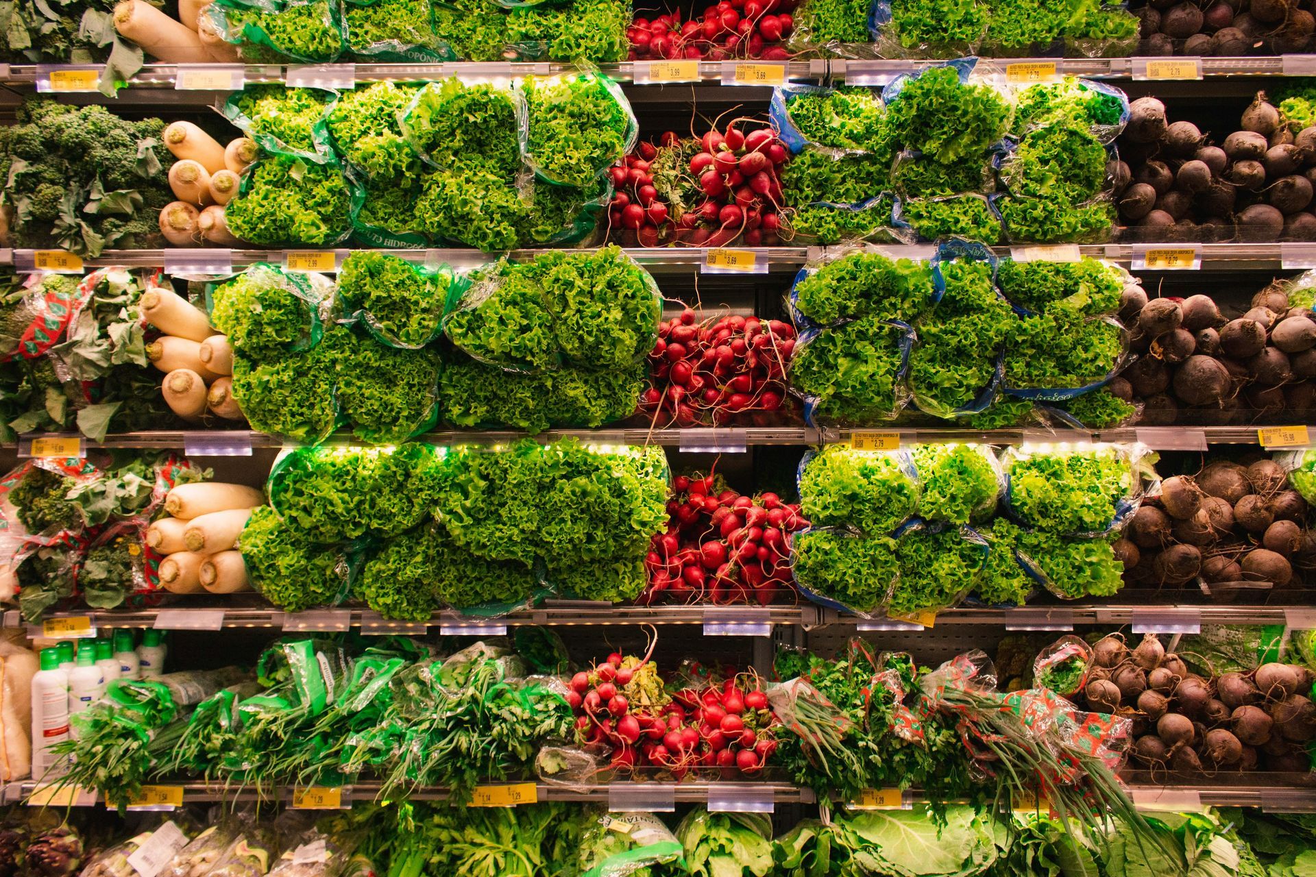 A red shopping basket filled with fruits and vegetables in a grocery store