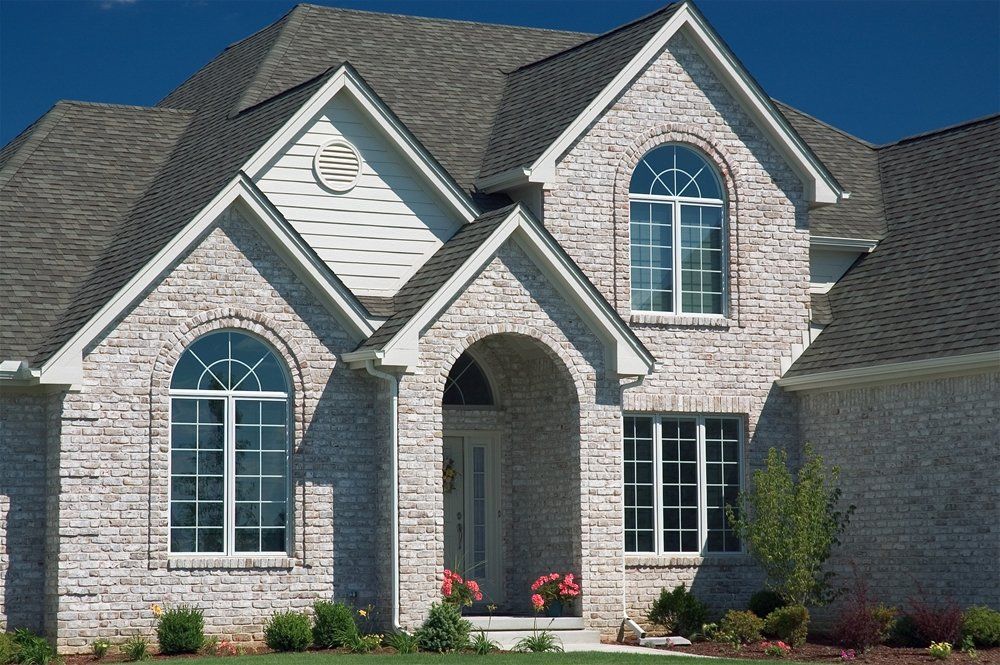 A white brick house with arched windows and a gray roof featuring home services in the Southeastern Michigan area
