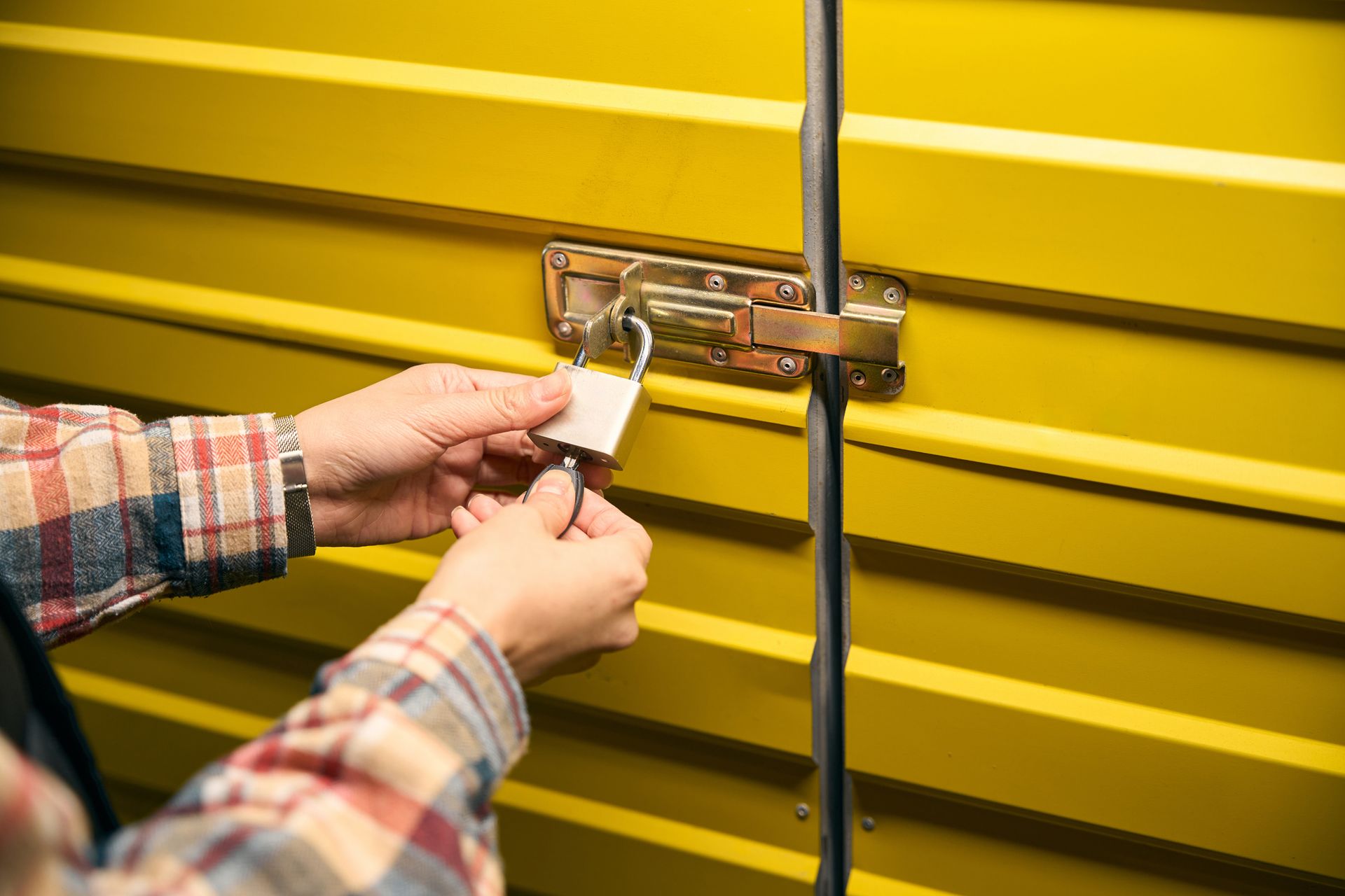 Warehouse worker hands padlocking metal storage unit door - Self Storage Company