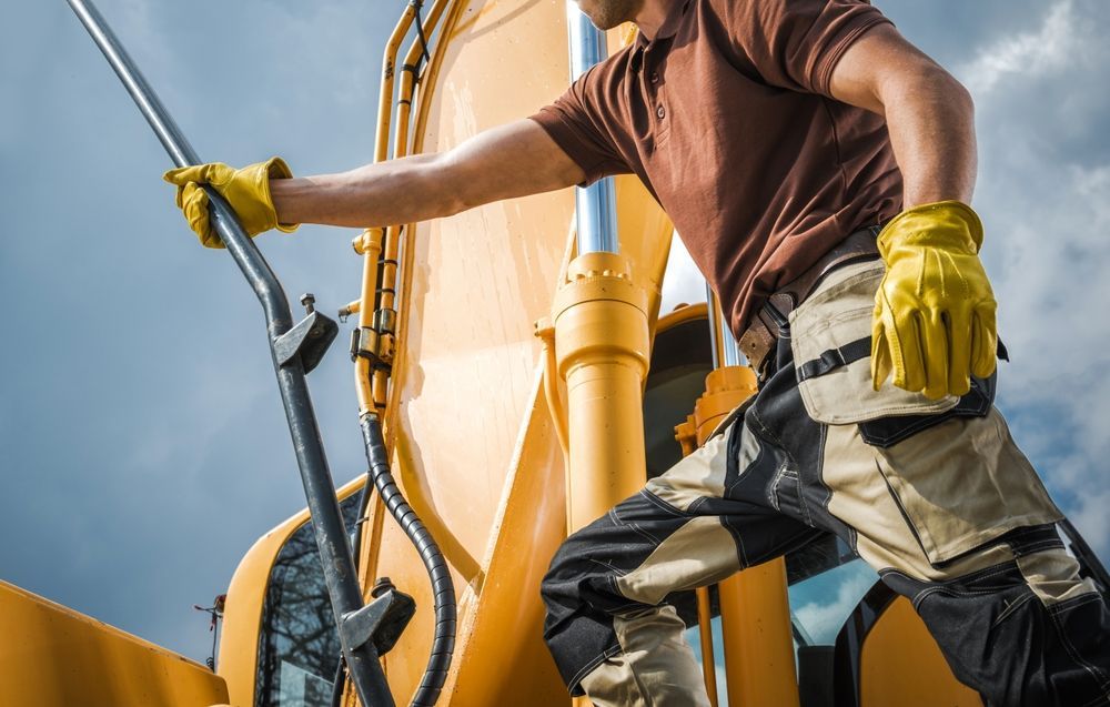 Person in Work Clothes Climbing Onto Yellow Construction Equipment — Waite Diesel Service in Douglas, QLD
