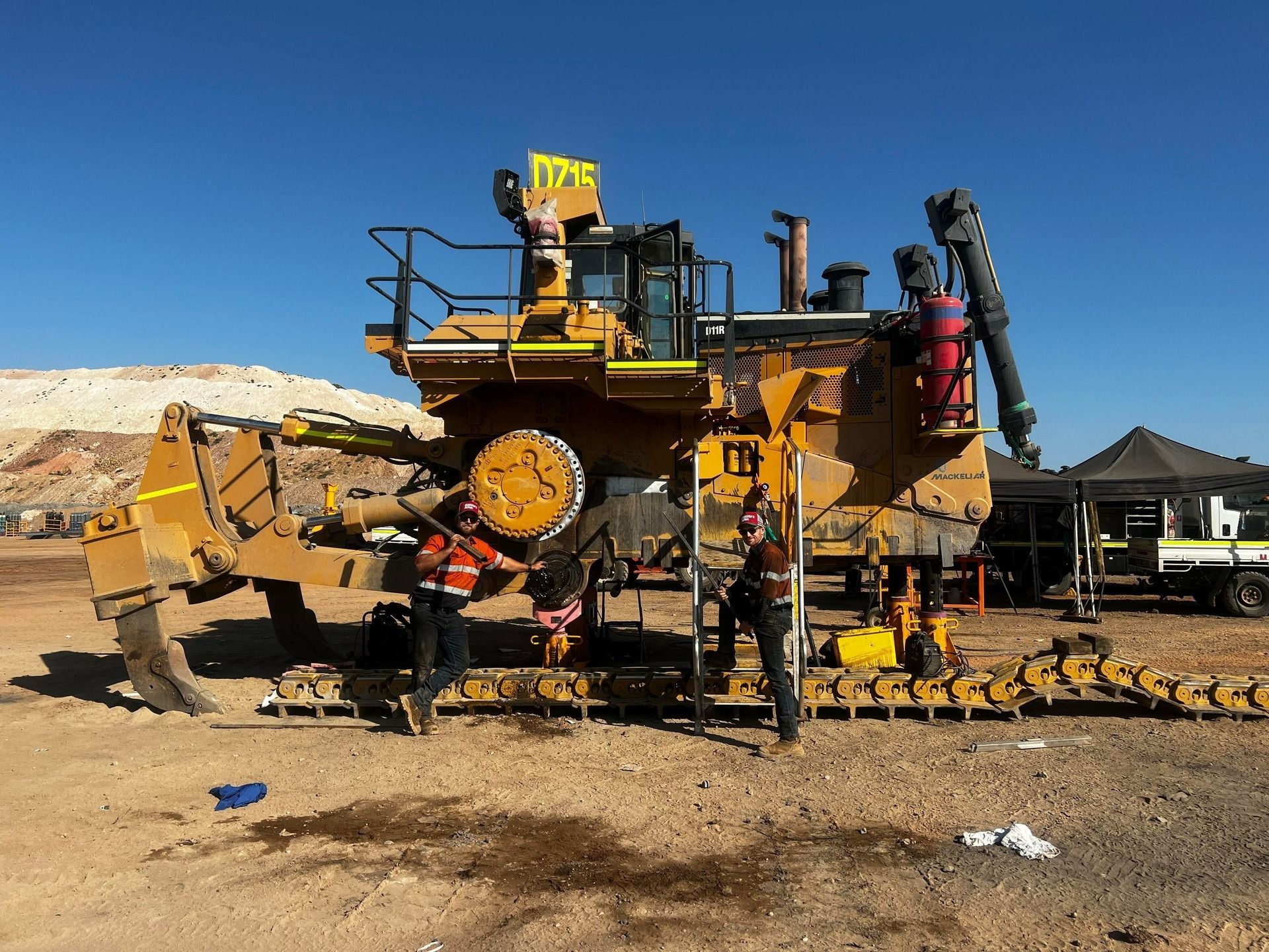 Two People Standing Next to a Large Yellow Mining — Waite Diesel Service in Douglas, QLD