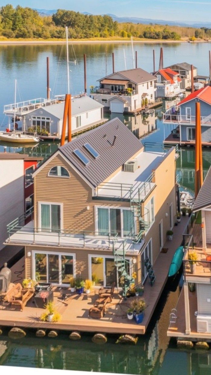 Houseboats on a waterway with tan siding, blue water, and a backdrop of trees.