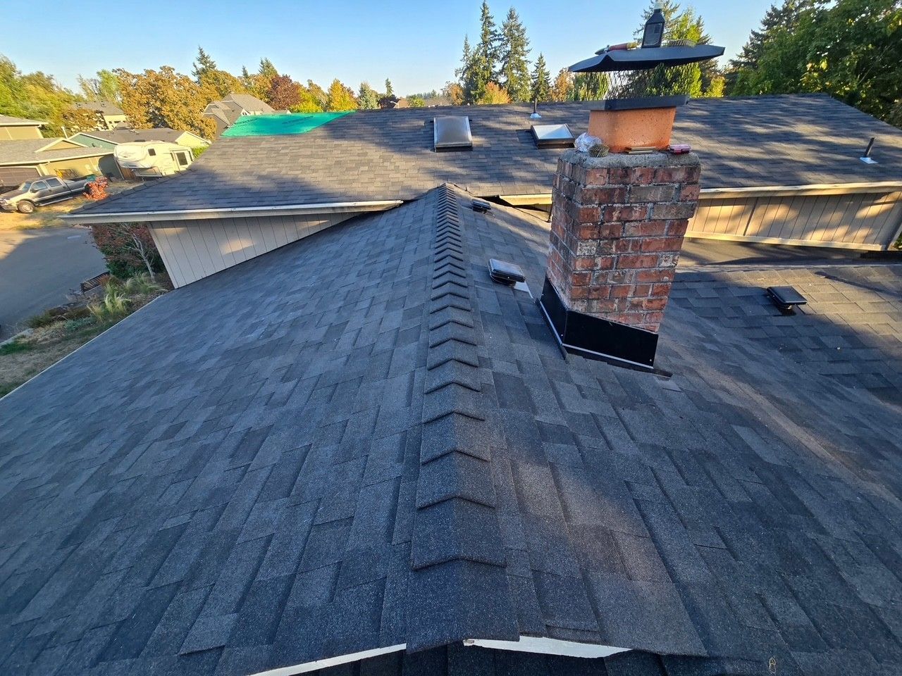 Dark gray shingle roof with a brick chimney, seen from above.