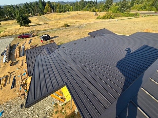 Dark gray metal roof under construction, set in a field.