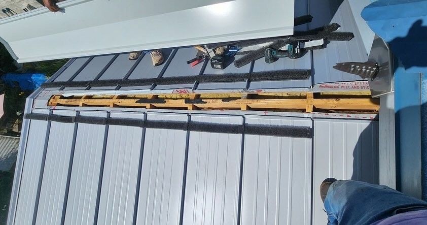 Metal roof construction with tools and workers visible.