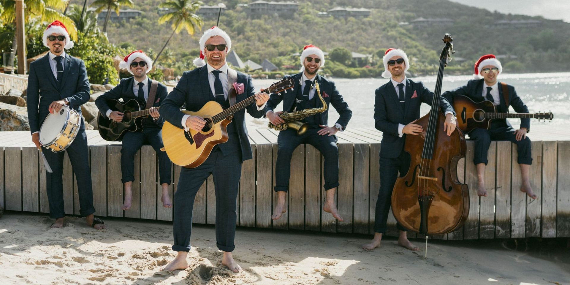 A group of men in suits and santa hats are playing instruments.