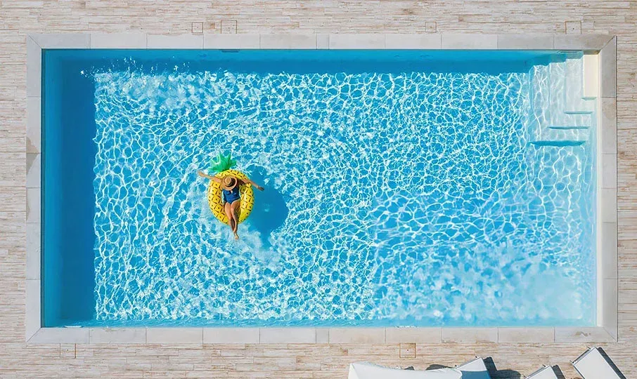 A person floating in a bright blue rectangular pool on a yellow pineapple-shaped inflatable ring.  — East Coast Pool Resurfacing In Port Macquarie, NSW