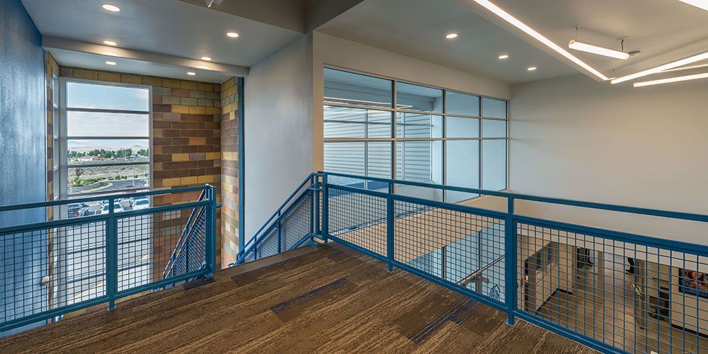 A hallway with stairs and a blue railing in a building.