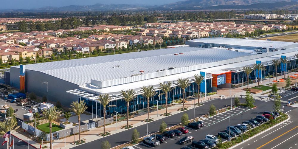 An aerial view of a large building with a lot of cars parked in front of it.