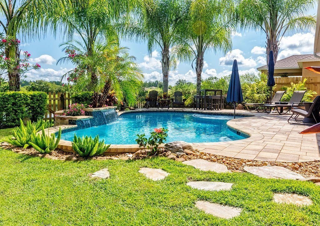 Swimming pool surrounded by palm trees and tropical plants.