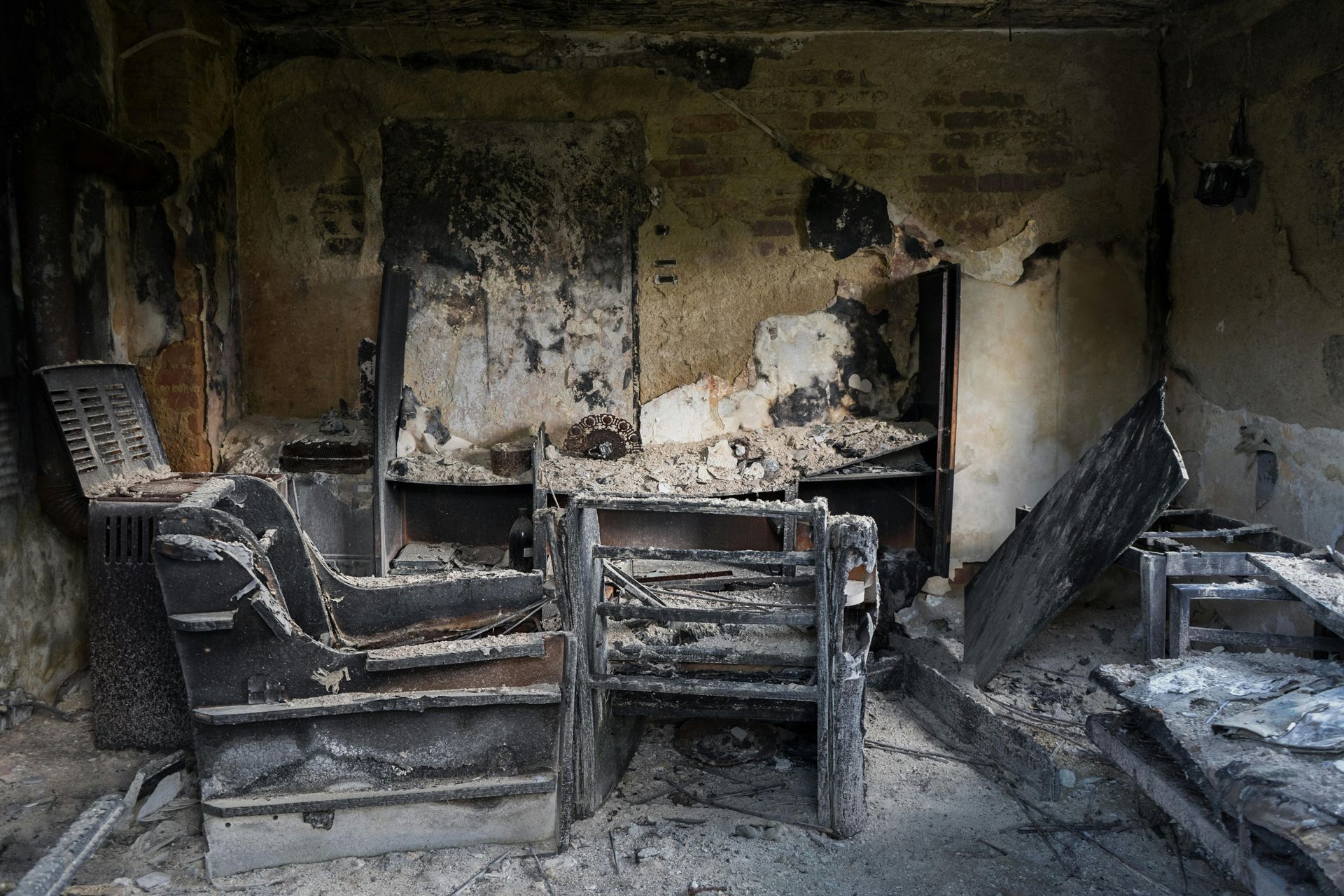 A room severely damaged by fire, with charred walls and blackened, destroyed furniture.