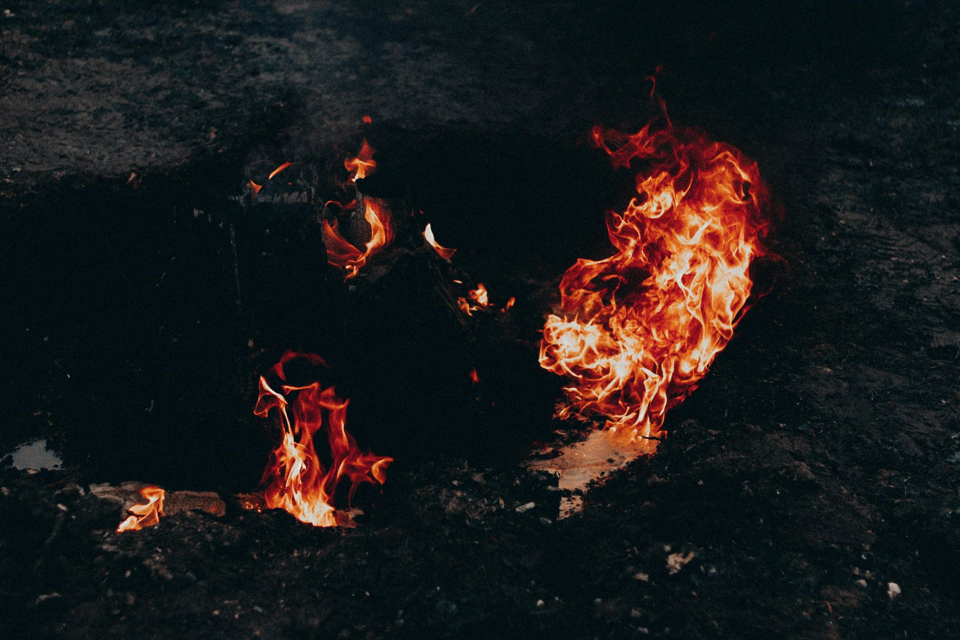 The underside of a mobile home structure featuring a metal frame, concrete piers, and ground covered by a vapor barrier.