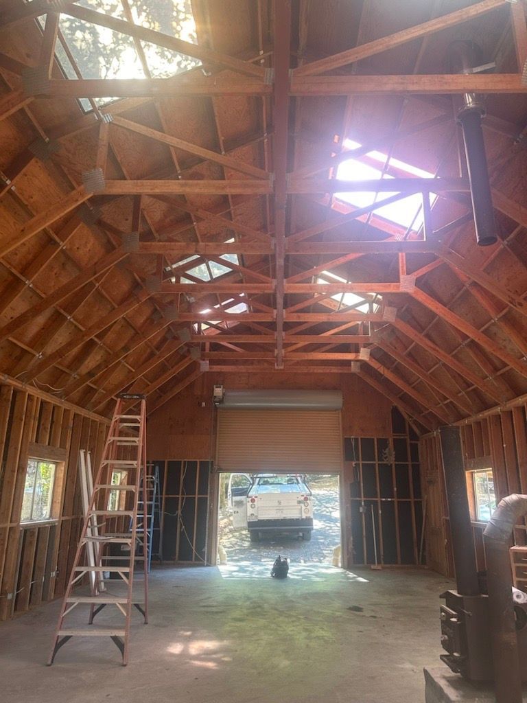 The inside of a building under construction with a ladder and a garage door.