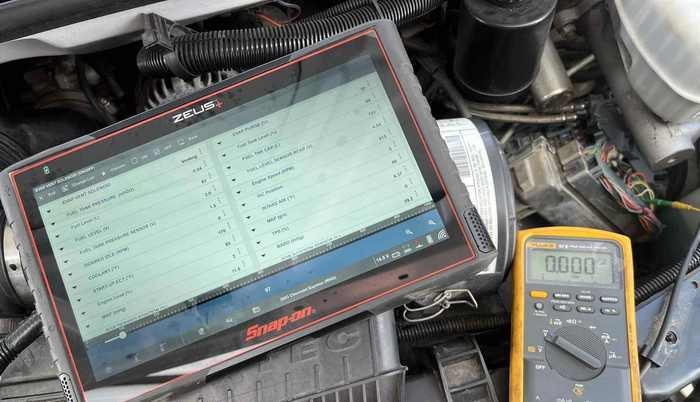 A Snap-on diagnostic tablet and multimeter on an engine bay, likely for automotive troubleshooting.