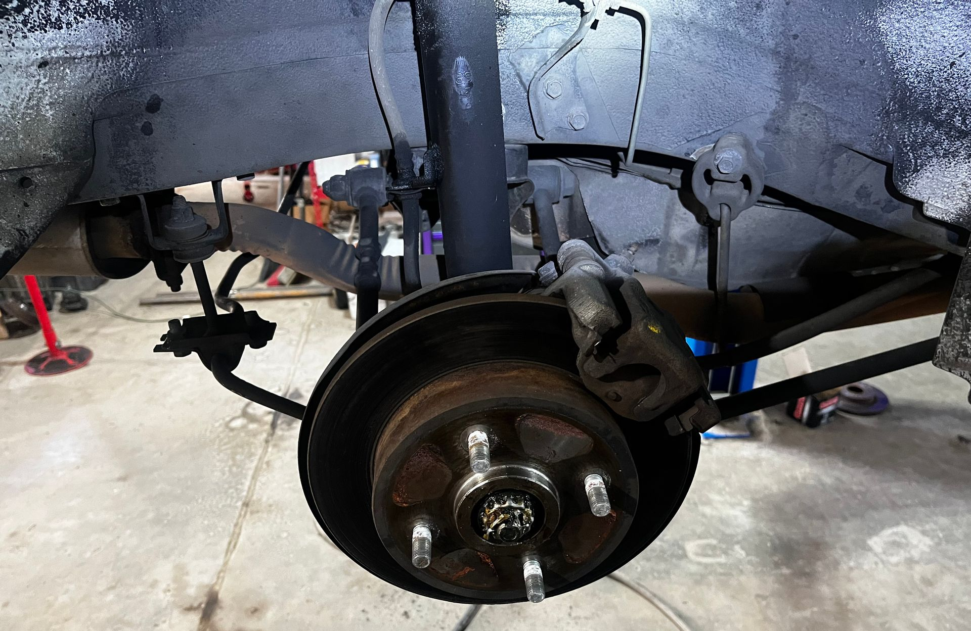 Rear car suspension assembly, showing a brake rotor, shock absorber, and suspension arms.