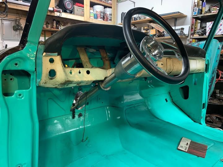 Teal car interior: steering wheel, dashboard, floor, and body panels. Restoration in progress.