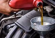 Pouring motor oil into a car engine through a funnel.