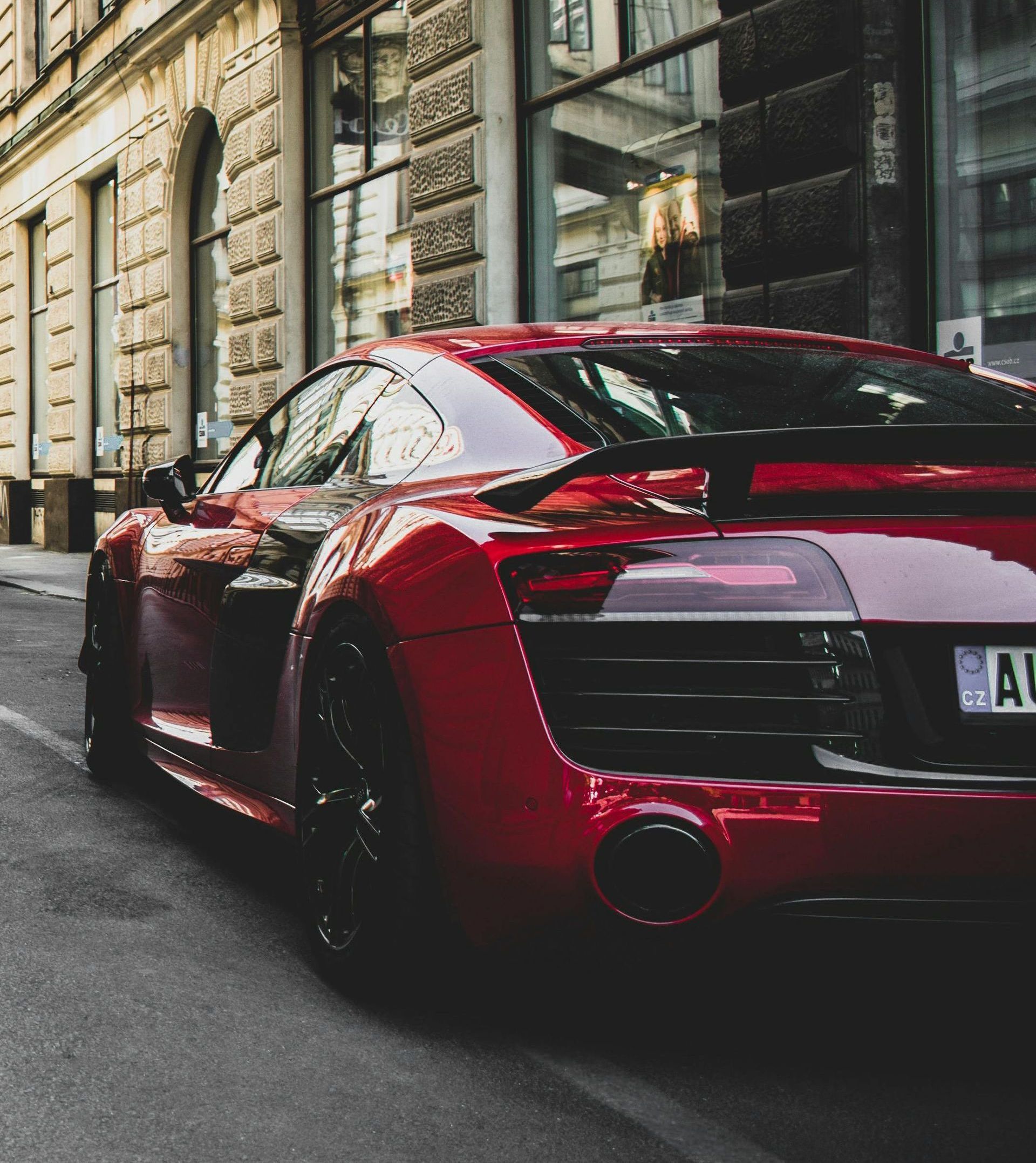 Red sports car parked on a city street, showcasing its rear end.